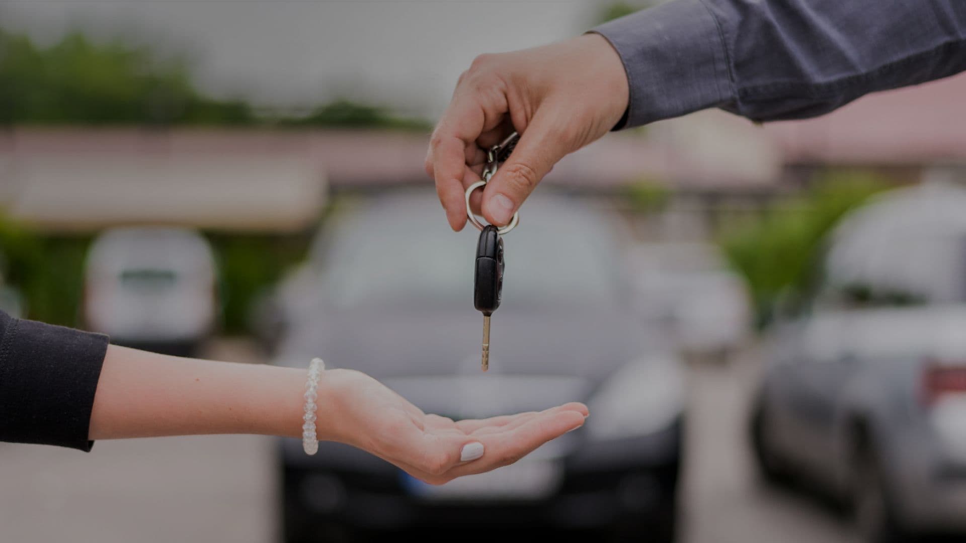 A hand holding a car key above another hand