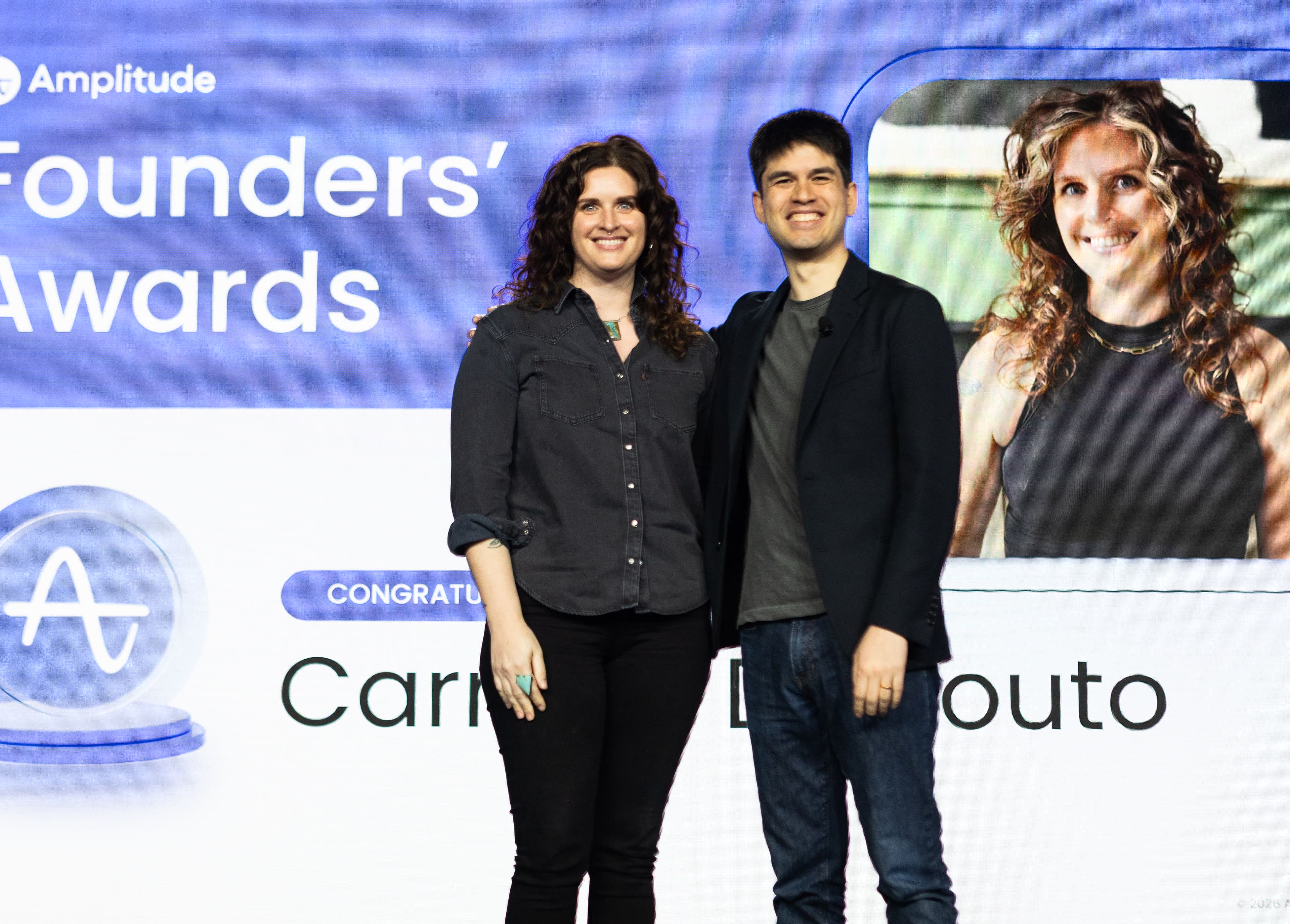Carmen DeCouto with Amplitude CEO Spenser Skates on stage acknowledging her 2025 Founders' Award.