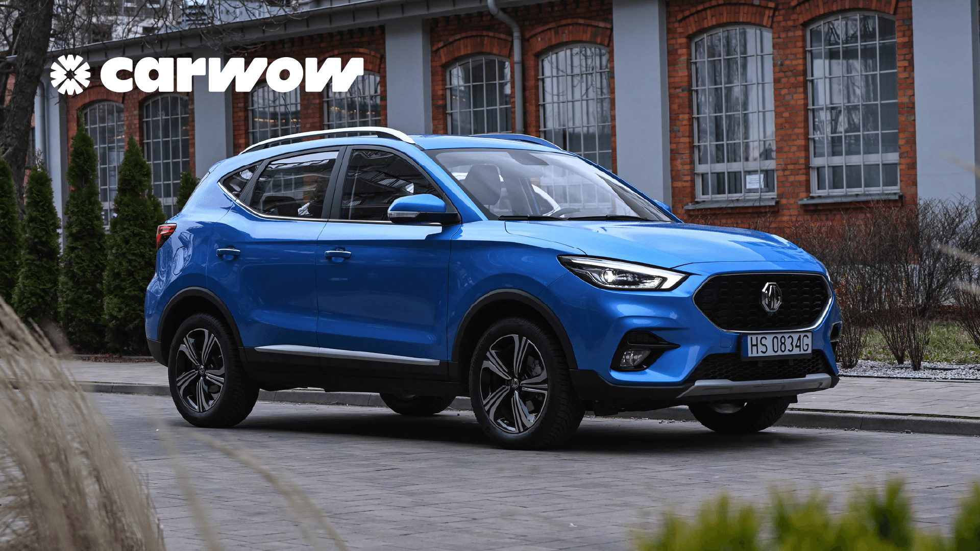 A blue station wagon parked in front of a brick building with the carwow logo in the top left corner