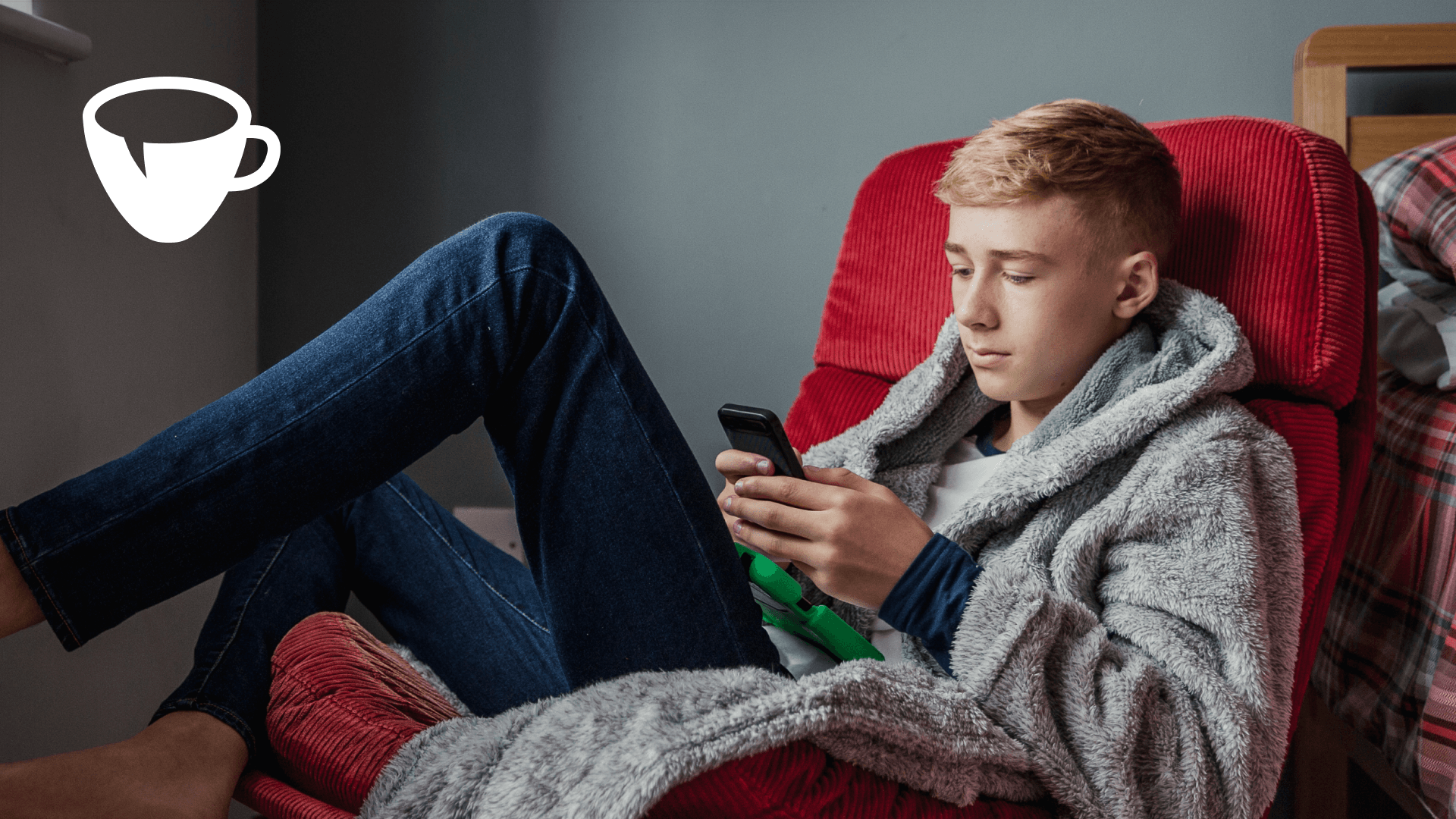Boy Looking at Phone and Sitting on Red Chair